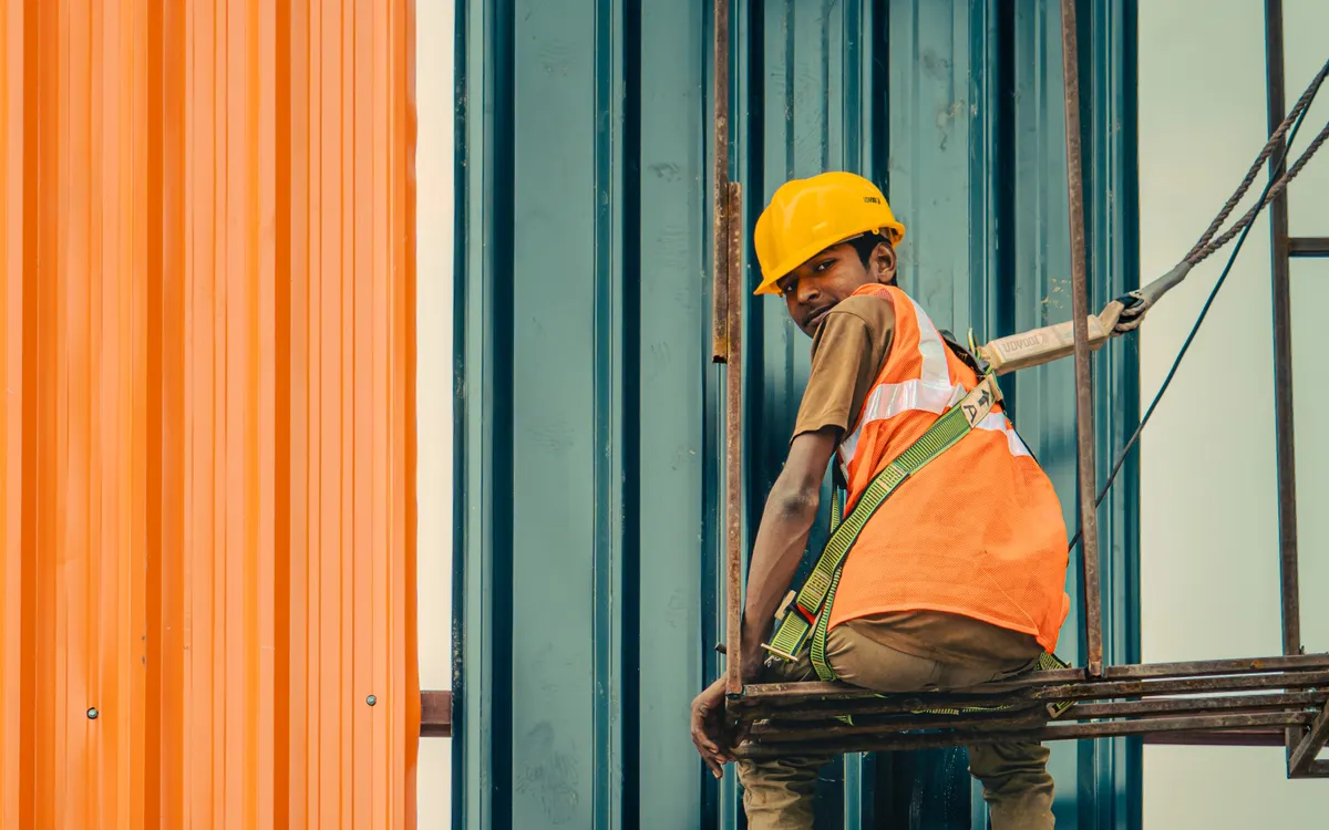Trabajador con equipo de seguridad sobre una estructura de andamios