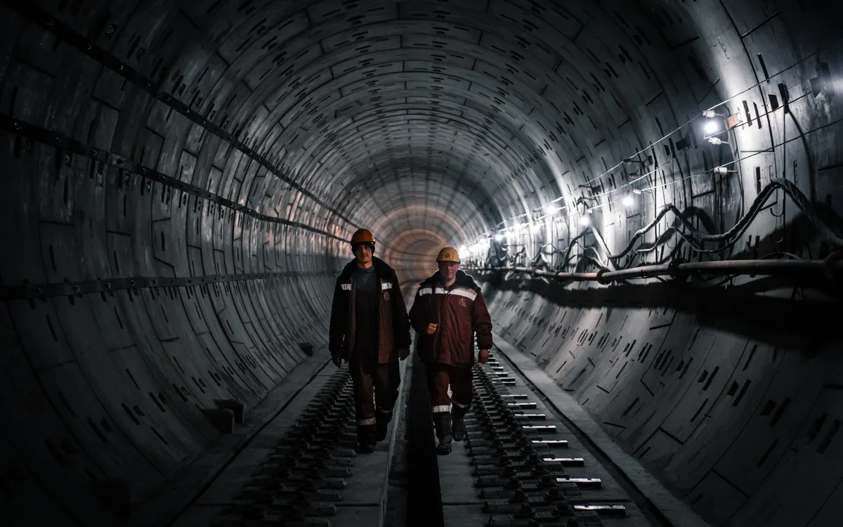 Trabajadores con casco recorriendo un túnel industrial